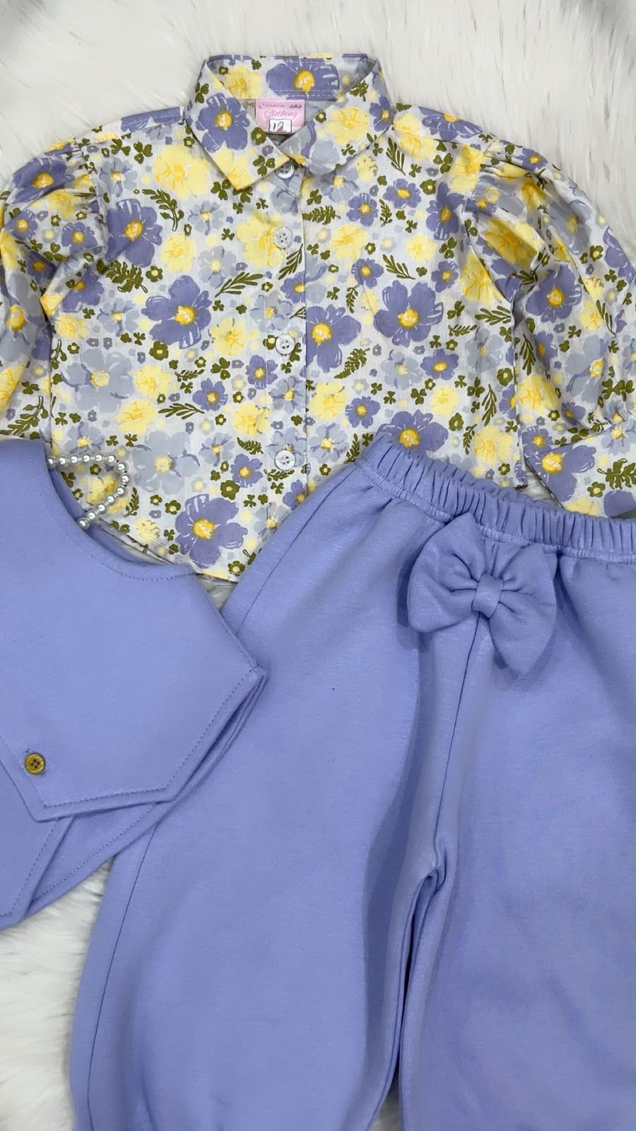 Multi-piece baby or toddler girl outfit set featuring a floral print long-sleeve collared shirt, a lilac waistcoat vest, and matching lilac cuffed trousers with a bow detail fleece winter stuff