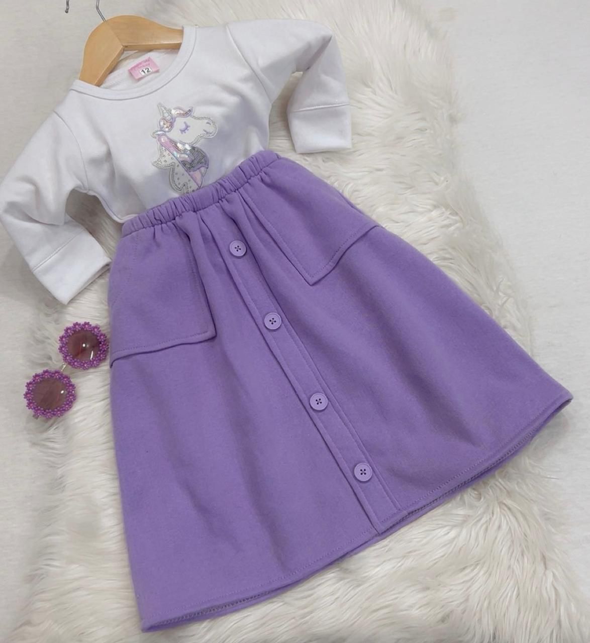 Two-piece girl's outfit featuring a white long-sleeve top with a unicorn graphic and a button-front lilac skirt fleeced stuff