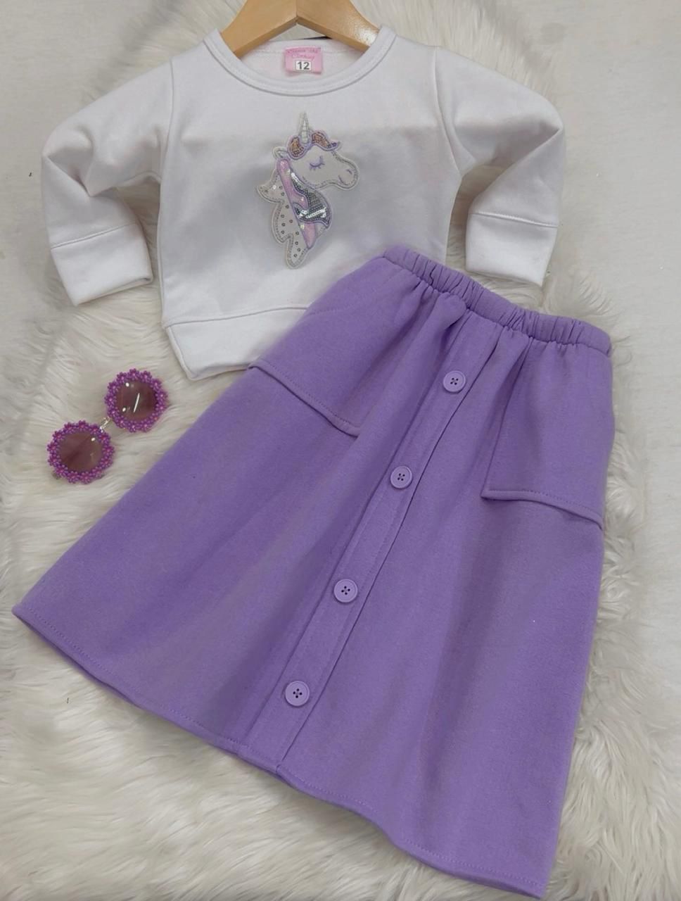 Two-piece girl's outfit featuring a white long-sleeve top with a unicorn graphic and a button-front lilac skirt fleeced stuff