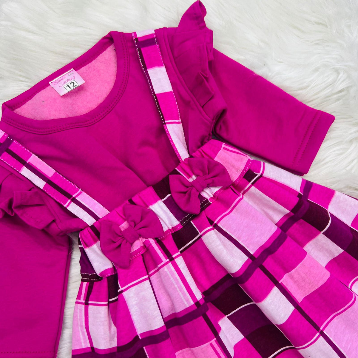 A bright pink long-sleeve top paired with a matching pink and magenta plaid suspender skirt fleece