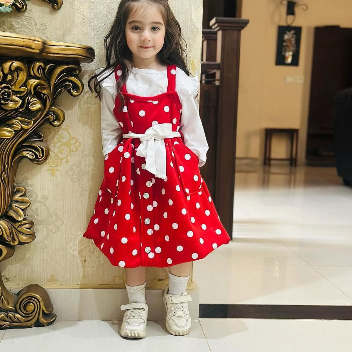 A red and white polka-dot baby girl overall dress paired with a white long-sleeve shirt fleece stuff